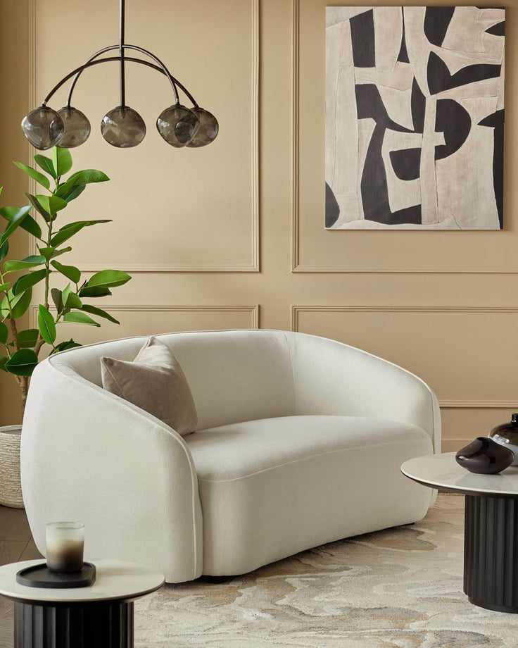 Stylish living room featuring a modern white sofa, abstract art, and complementary coffee tables. Perfect for contemporary homes.