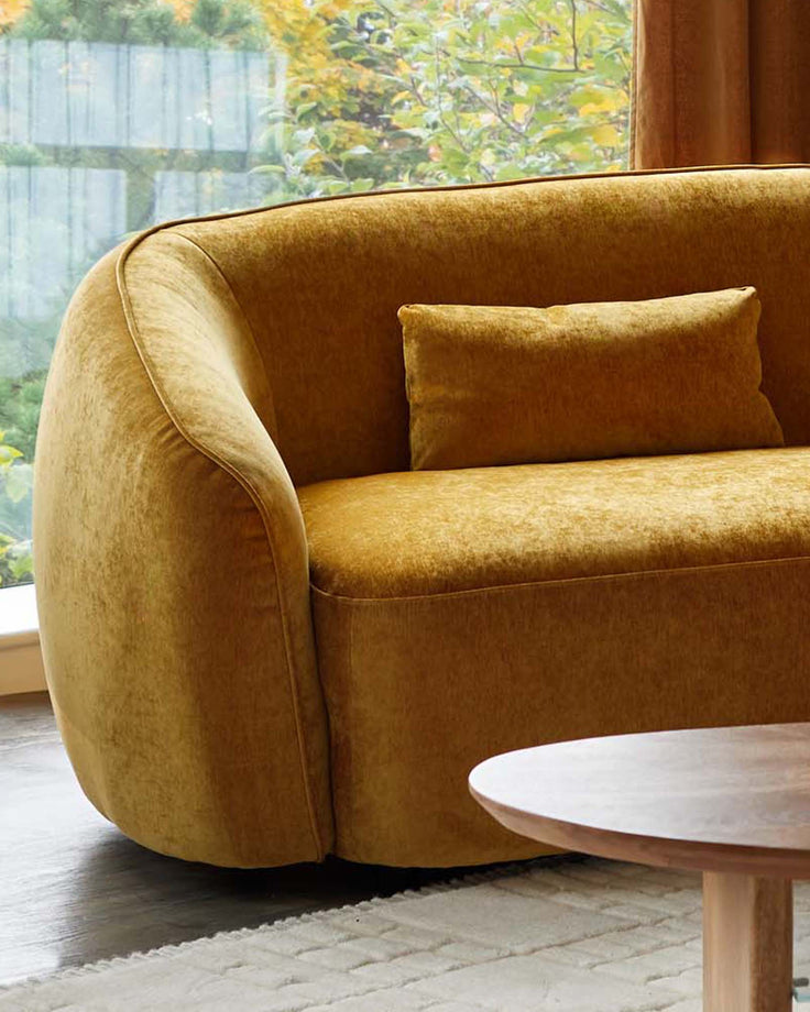 Stylish mustard velvet sofa with a wooden coffee table, creating a cosy and modern living room vibe.
