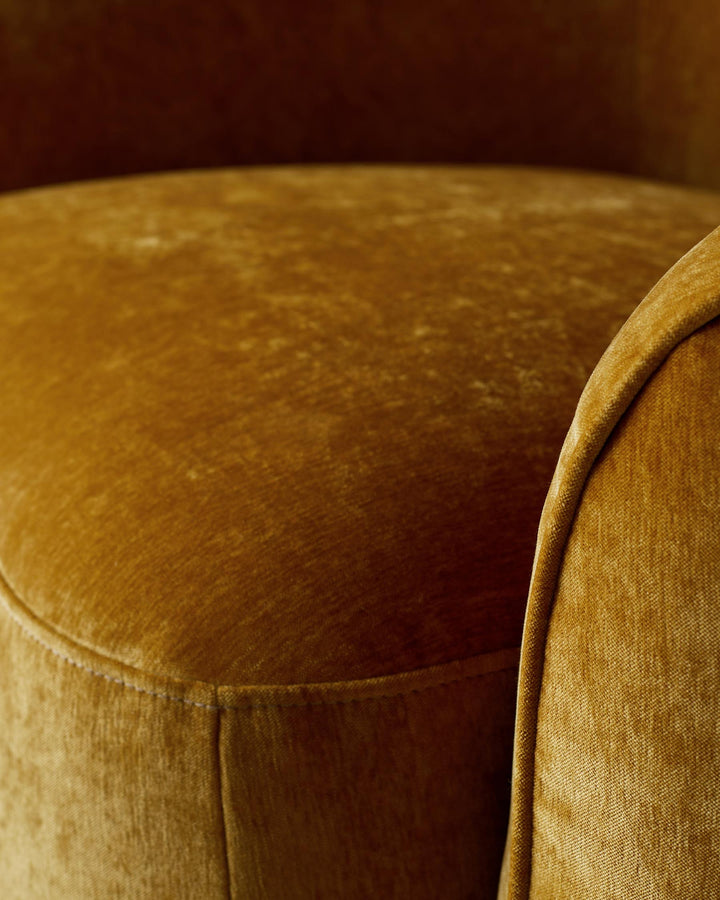 Close-up of a gold velvet chair, showcasing its luxurious texture and curved design.