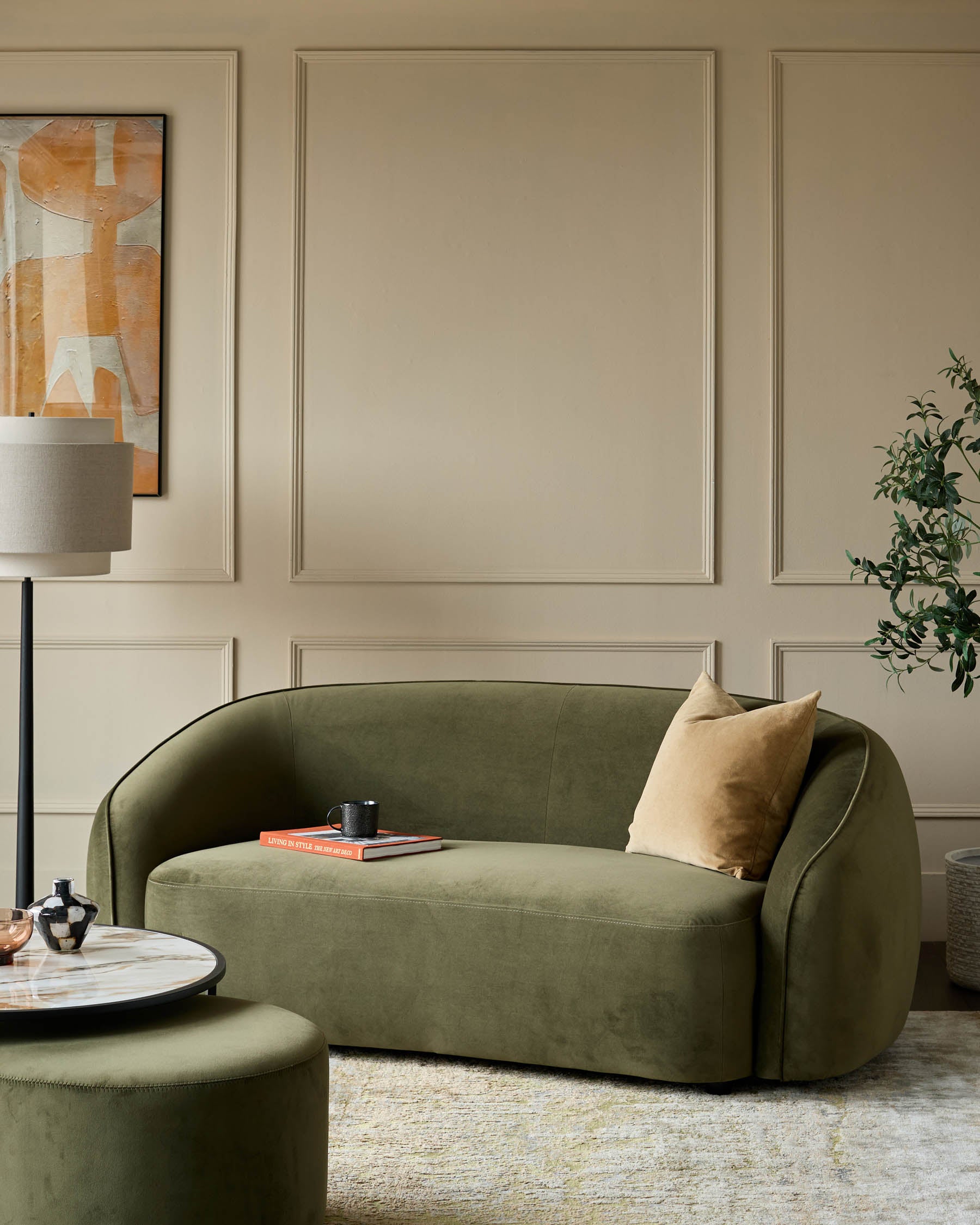 Green velvet sofa with neutral cushions and a matching ottoman creates an inviting, stylish living space.