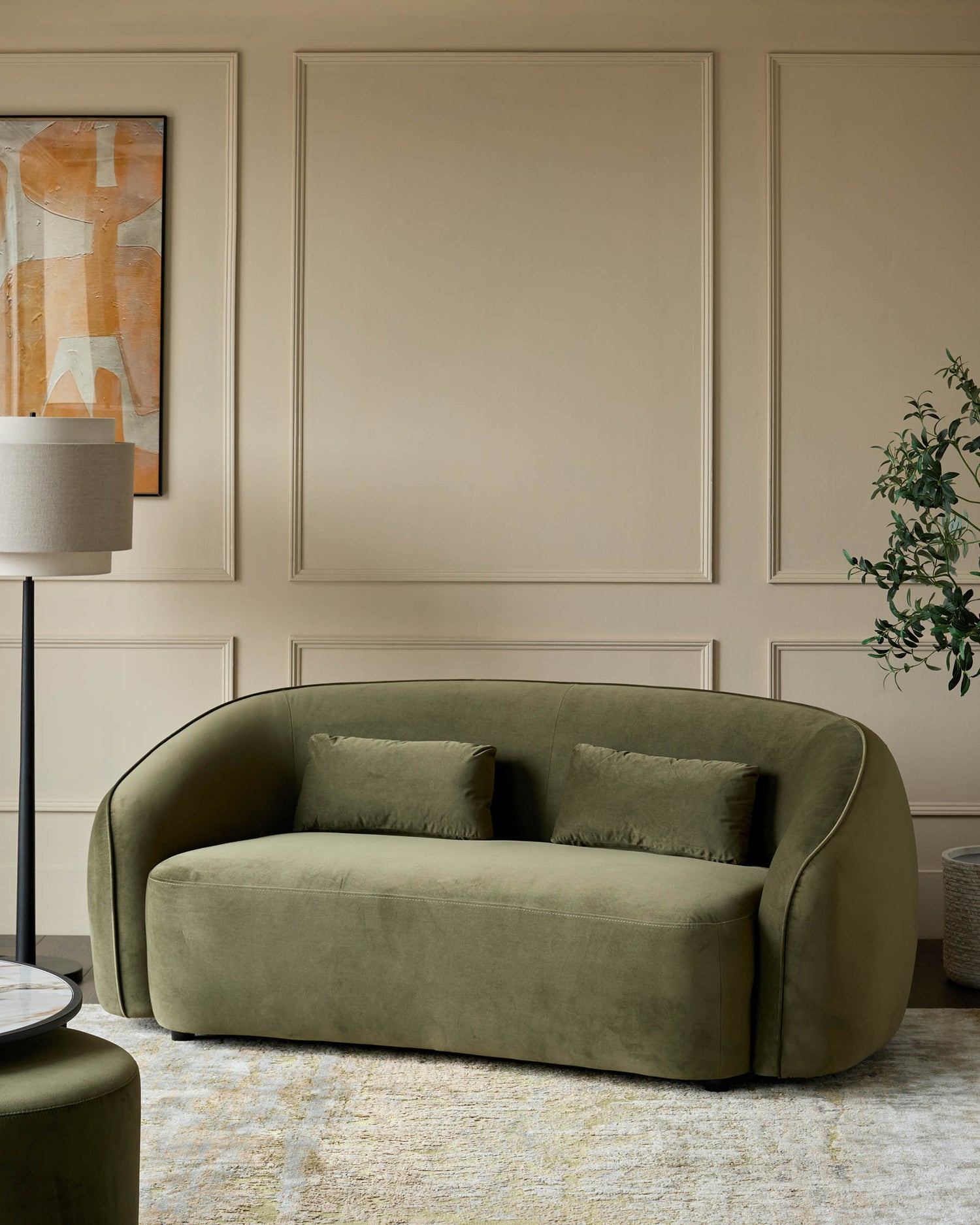 Stylish olive green velvet sofa with matching cushions, a modern floor lamp, and a coordinating ottoman, creating a luxe living space.
