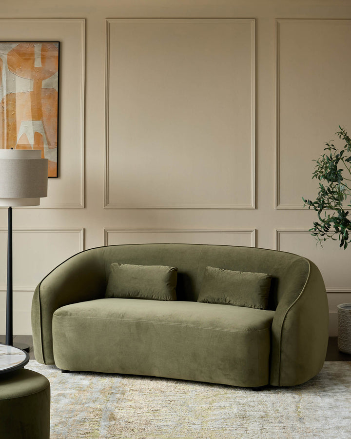 Stylish olive green velvet sofa with matching cushions, a modern floor lamp, and a coordinating ottoman, creating a luxe living space.