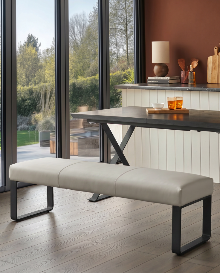 Loop 3-seater bench without backrest, light grey upholstery, black metal legs, shown in modern kitchen with garden view.