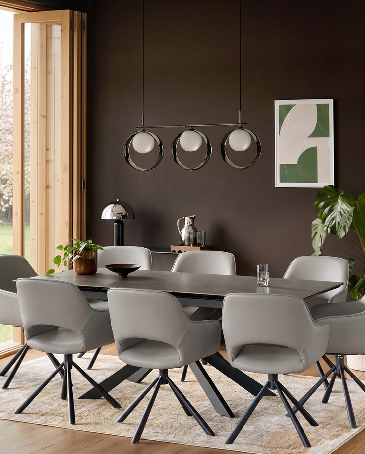 Marlow light grey leather swivel dining armchair with black metal legs, shown in modern dining room setting around dark table.