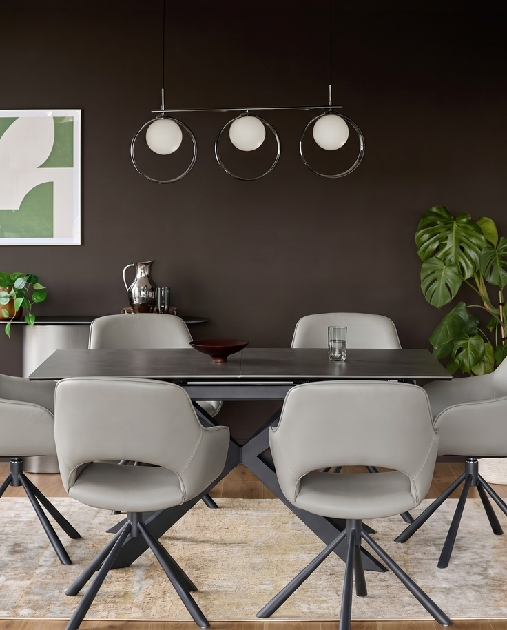 Marlow light grey leather swivel dining armchair with black star base, shown at dining table in contemporary room setting.