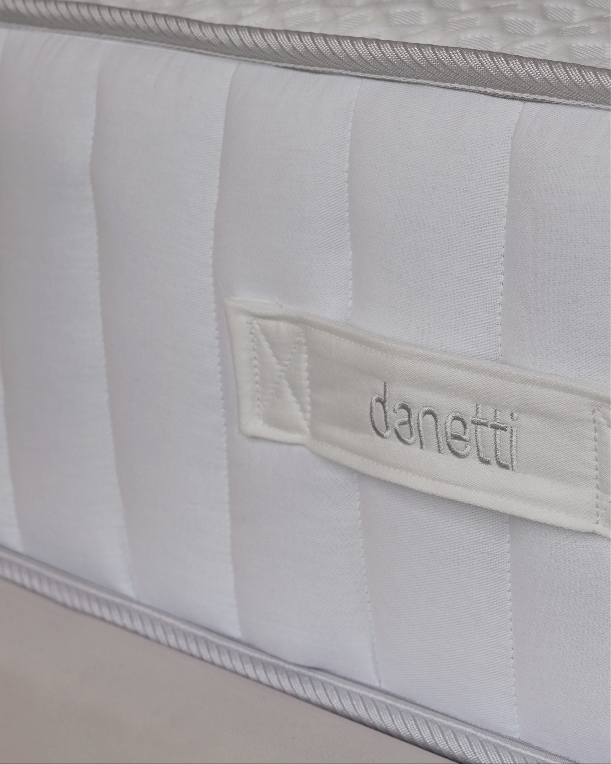 A plush mattress with a quilted top, paired with two soft pillows, set against a stylish upholstered headboard.