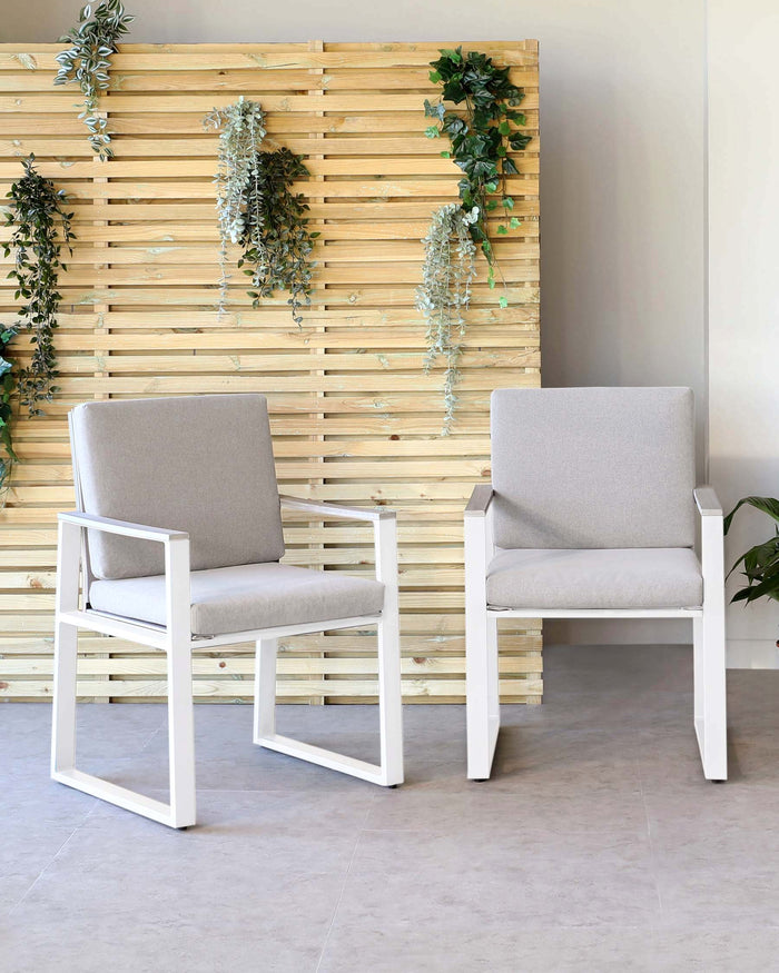 Two modern minimalist armchairs with white frames and light grey upholstery.