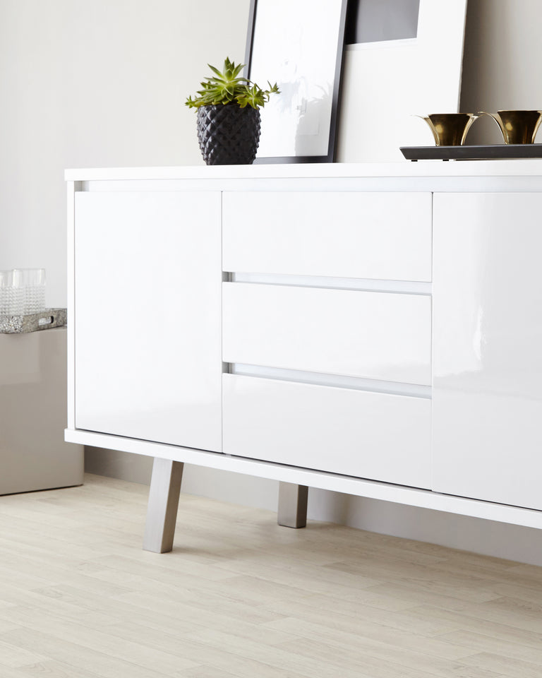 Modern white sideboard with sleek finish, featuring three drawers with no visible handles, standing on minimalist metal legs.