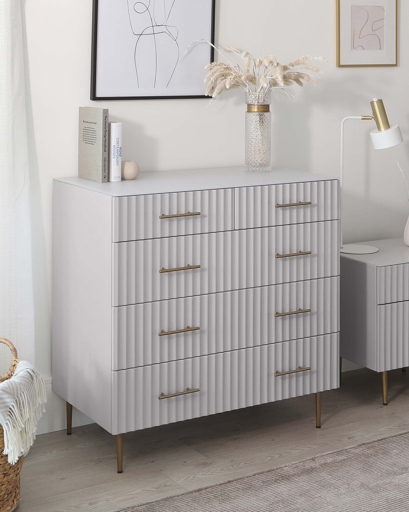 Modern grey fluted dresser with brass handles and matching bedside table, set in a stylish room with neutral decor.
