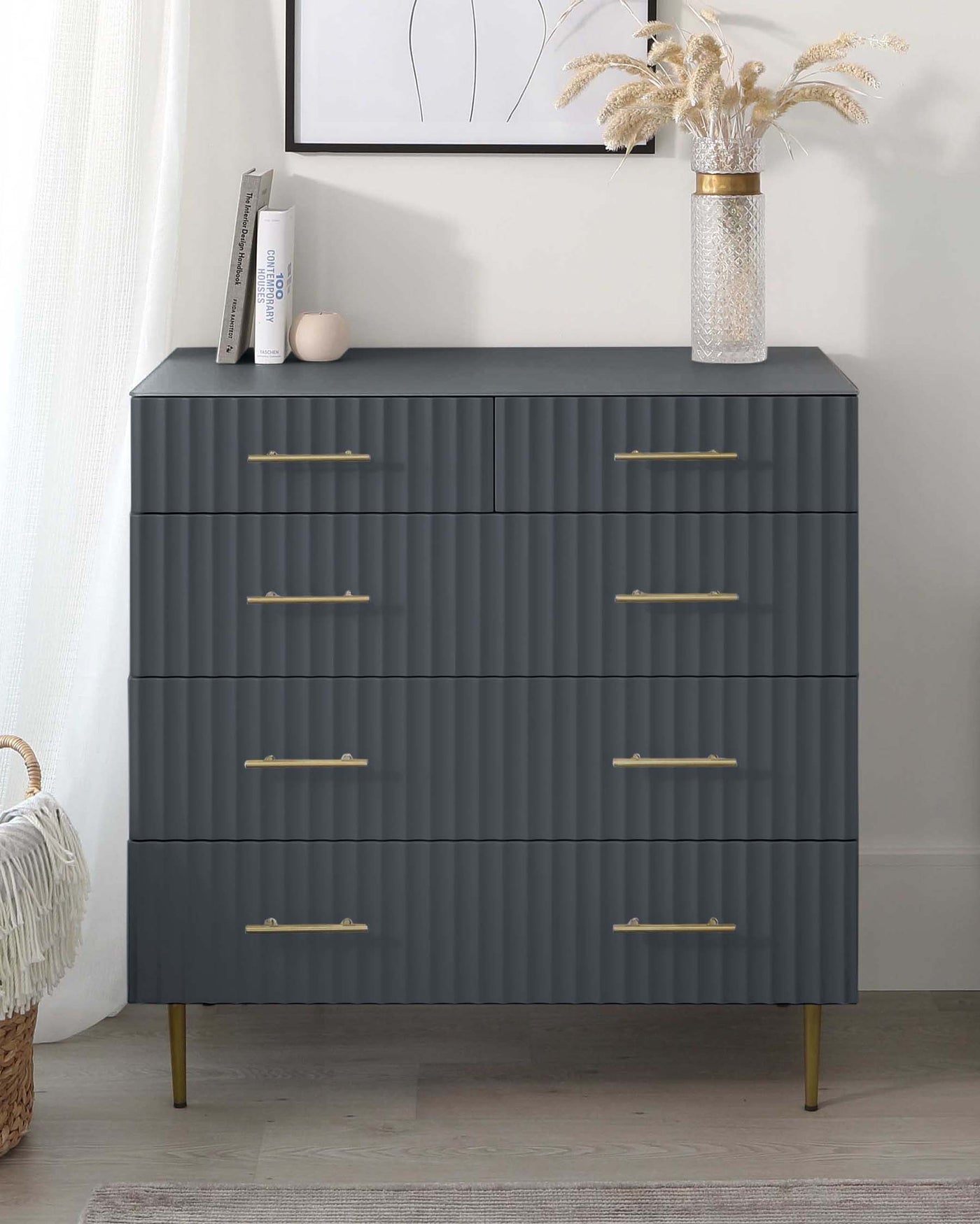 A modern charcoal grey dresser with six drawers, featuring a textured front and brass-finish handles, supported by four tapered metal legs in a matching brass finish.