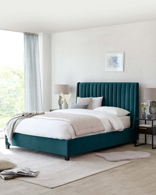 Elegant bedroom furniture featuring a plush, teal upholstered bed with a tufted headboard, accompanied by a sleek, black-finished nightstand with an open shelf and a drawer. The bed is dressed in crisp white bedding with a cosy throw arranged at the foot. A soft beige area rug lies beneath, complementing the serene, neutral-toned room.