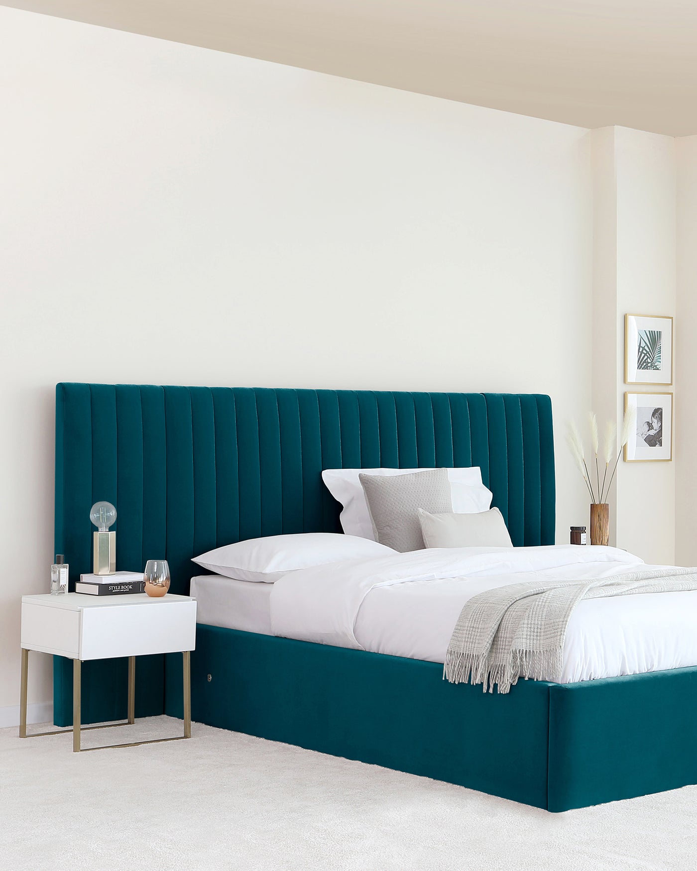 Luxurious, tall teal upholstered headboard with vertical channel tufting extending to the base of the bed, paired with a white modern nightstand featuring gold metal legs.