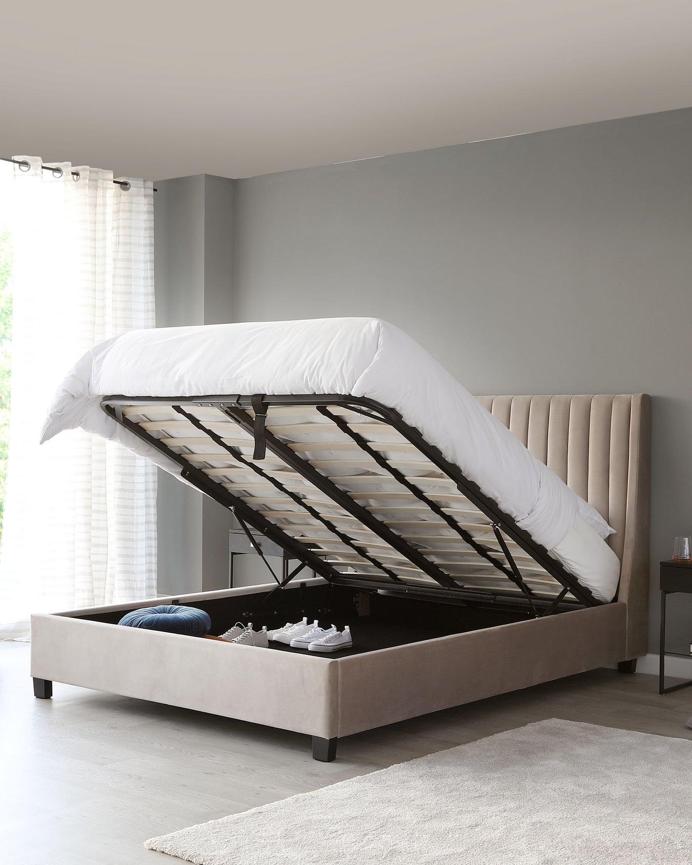Contemporary beige upholstered storage bed with a tufted headboard design, featuring a gas-lift mechanism to access the under-bed storage compartment.