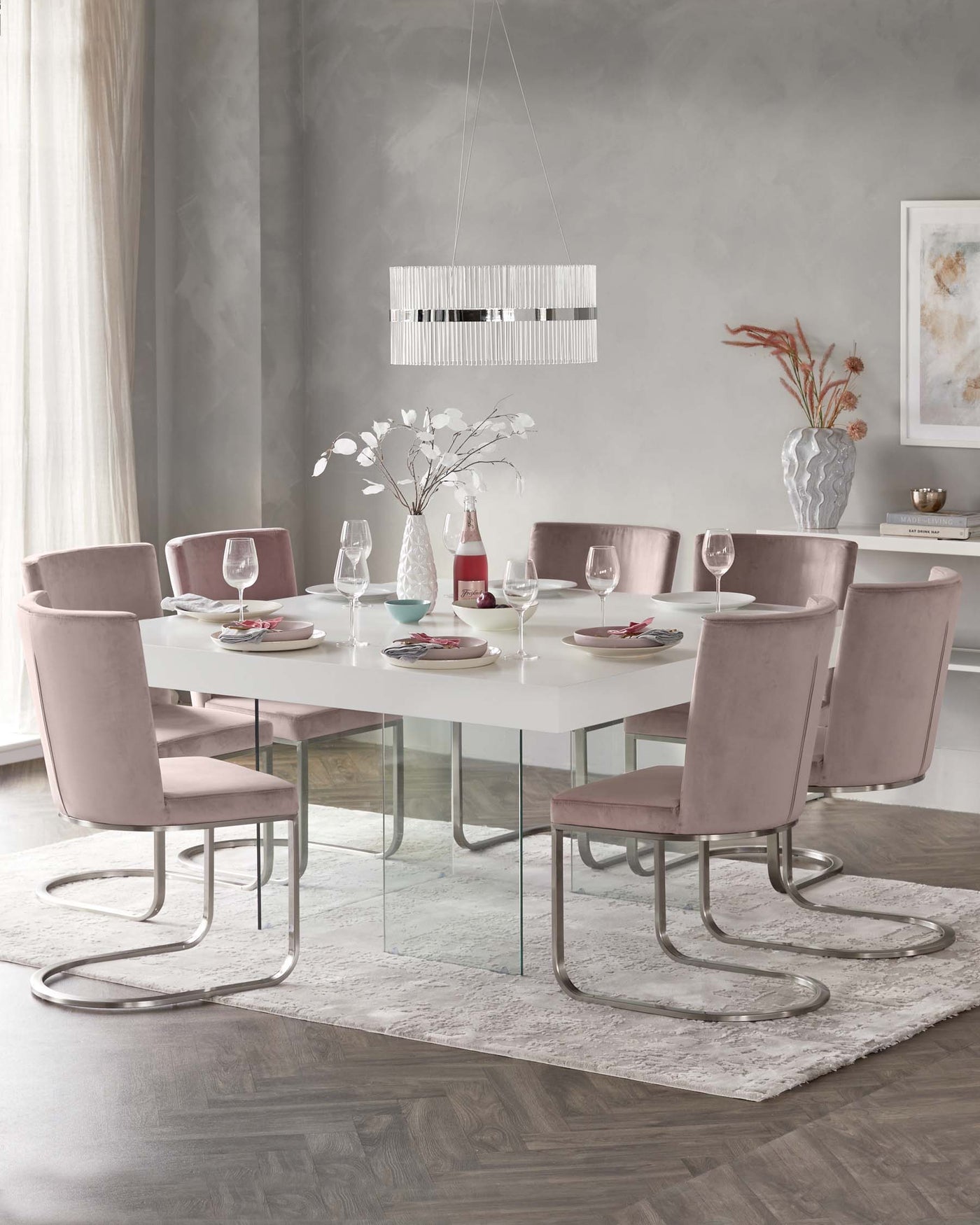 Modern dining room set with a rectangular glass-top table on a sleek metal base, surrounded by eight velvet-upholstered chairs with curved metal legs, showcased in a minimalist room with soft tones.
