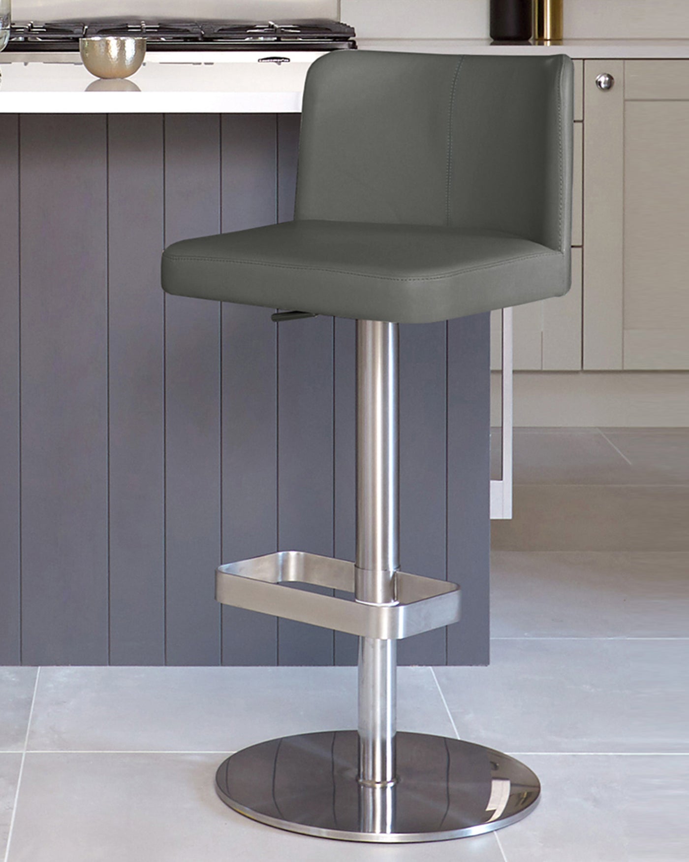 Modern adjustable-height bar stool with a sleek chrome pedestal base, built-in footrest, and a grey faux leather seat with a low backrest.