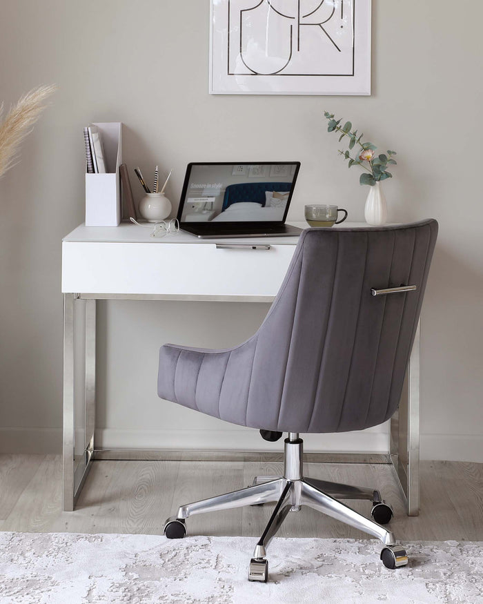 A modern home office setup featuring a sleek white desk with clean lines and chrome legs, accompanied by a stylish grey upholstered office chair with a high back, armrests, a metallic base, and casters for mobility.