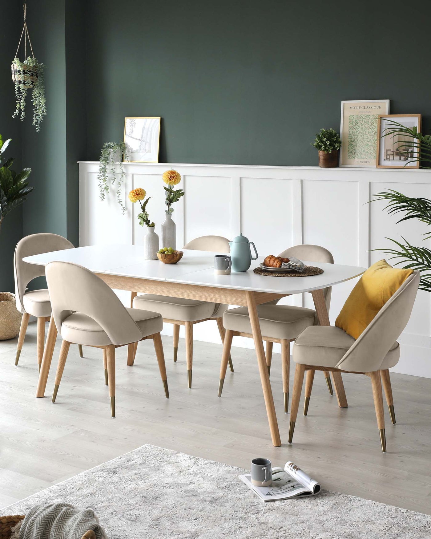 Modern dining room set featuring a white oval table with natural wood legs and a set of six matching upholstered chairs with smooth, beige fabric and tapered wood legs.