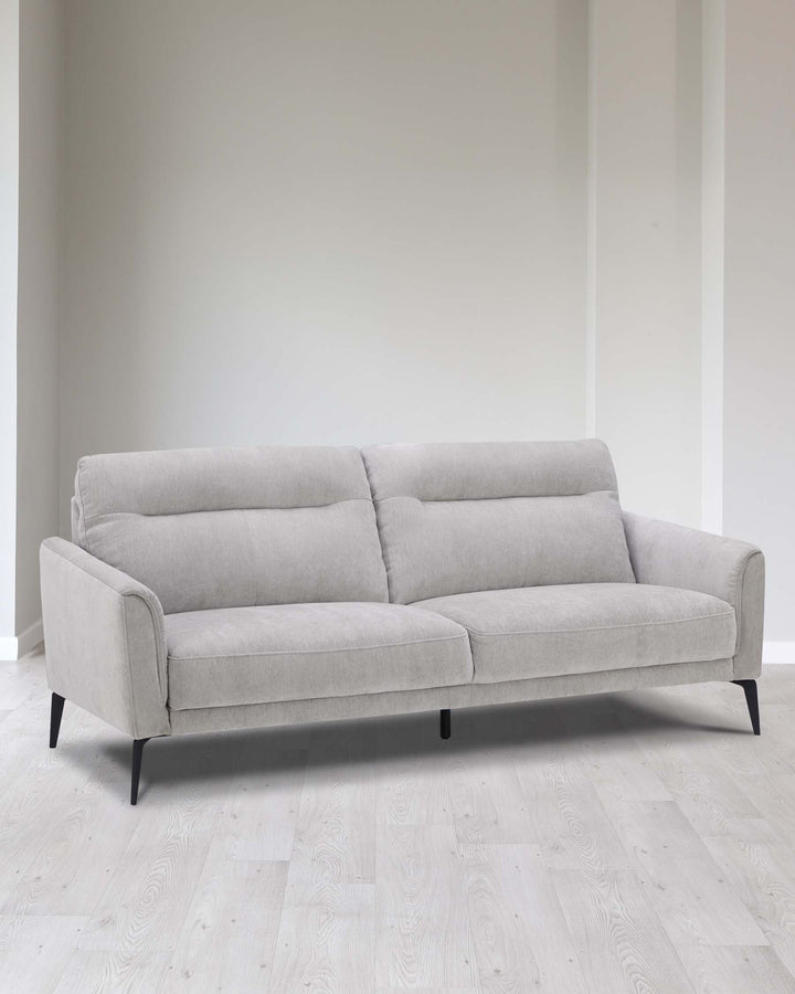 A modern three-seater sofa featuring light grey upholstery and slender, slightly tapering black legs. The sofa has a minimalist design with clean lines, gentle curves on the armrests, and a smooth fabric finish.