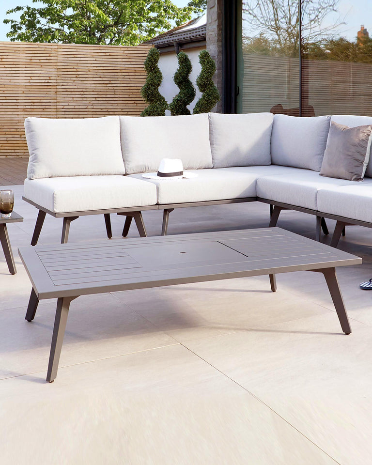 Contemporary outdoor furniture set featuring a light grey corner sectional sofa with plush cushions and a coordinating dark grey metal slatted coffee table.