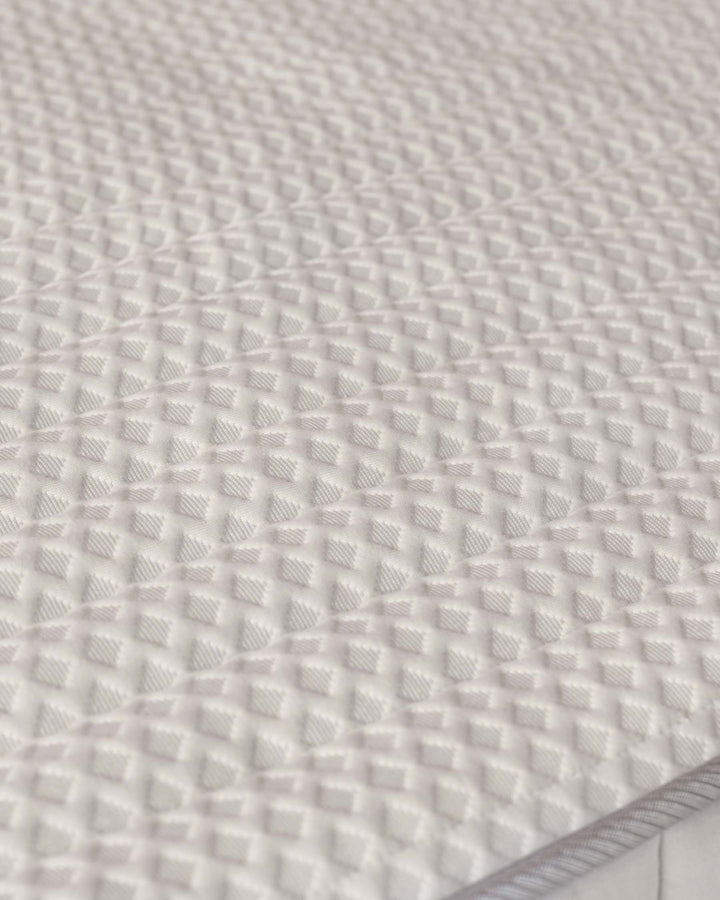 Close-up of a textured, white mattress surface. Shows off the quilting and soft feel of the mattress.