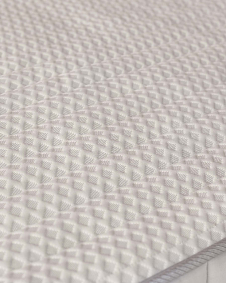 Close-up of a white mattress with a square patterned textured finish, offering a comfortable and stylish look.