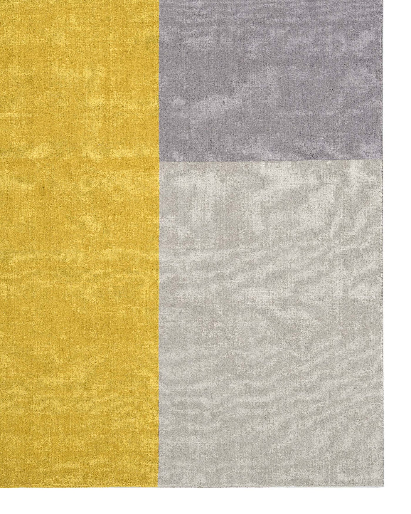 No furniture is displayed in the image; it features a geometric patterned rug with blocks of mustard yellow, light grey, medium grey, and off-white colours.