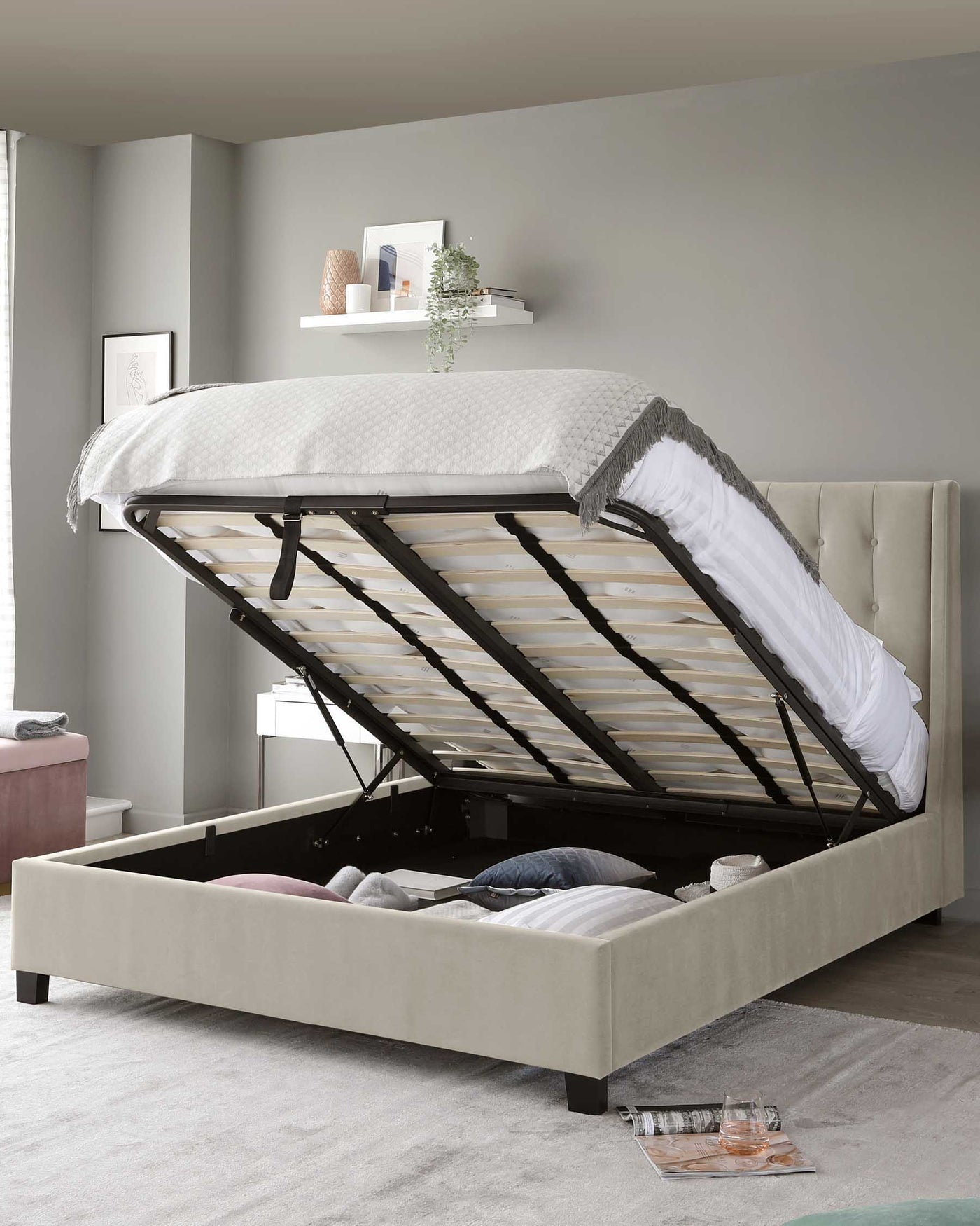 Upholstered platform storage bed in beige with an open lift-up frame revealing spacious under-bed storage, set in a contemporary bedroom setting with a neutral colour scheme.