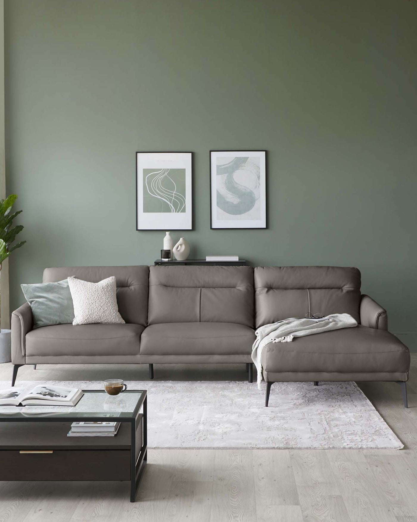 Modern L-shaped grey upholstered sectional sofa with multiple cushions, accompanied by a rectangular black metal coffee table with a glass top on a textured white area rug.