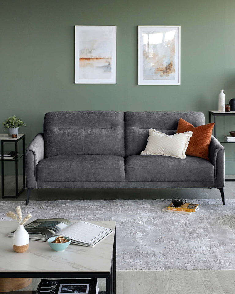 Modern minimalist living room featuring a sleek, dark grey upholstered sofa with clean lines and a rectangular side table finished in black with a green plant on top.