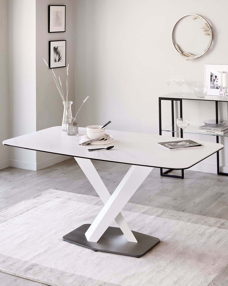 Modern minimalist dining table with a white rectangular top and a distinctive X-shaped metallic base, along with a sleek black console table featuring a glass top and slender metal frame, placed against a neutral-toned room with decorative wall art and a subtle area rug.