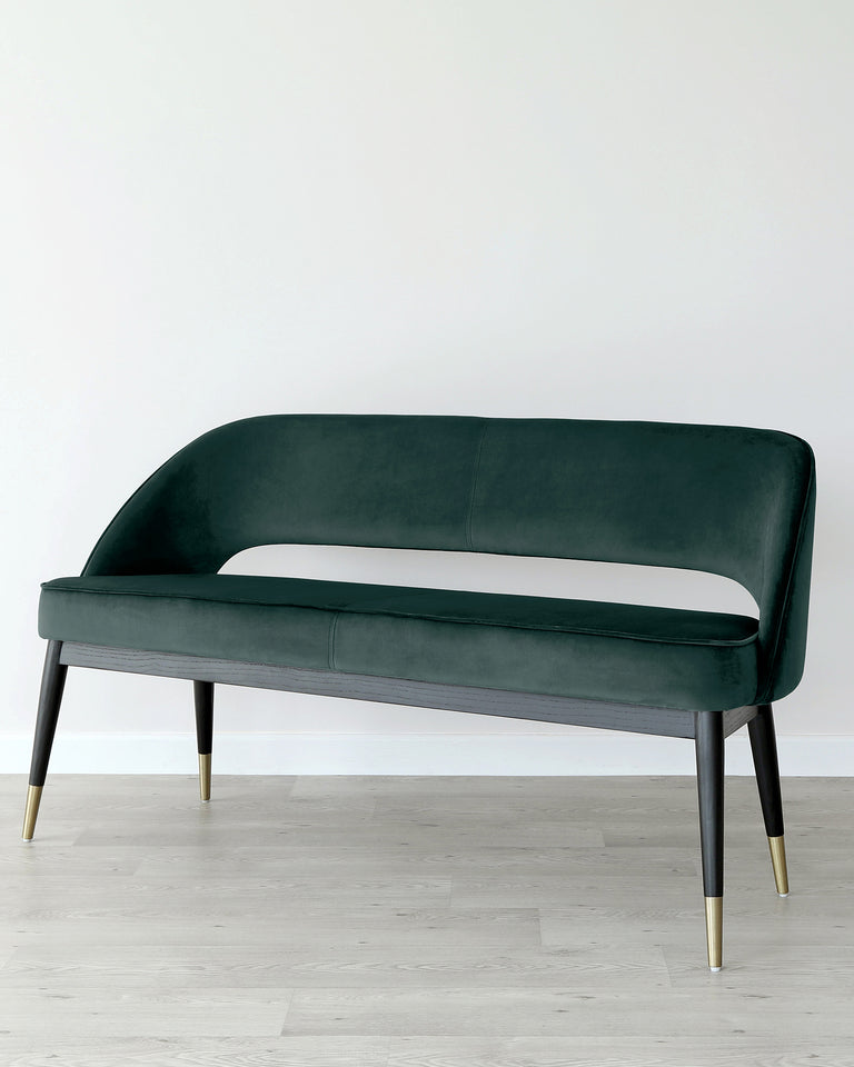 Elegant modern velvet loveseat with a curved backrest and seat, featuring dark green upholstery and four tapered wooden legs with brass-finished metal caps.
