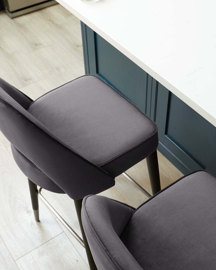 A modern charcoal-grey upholstered dining chair with a sleek silhouette and slender black metal legs positioned beside a white countertop with a teal blue base. The chair features a comfortable padded seat and backrest.