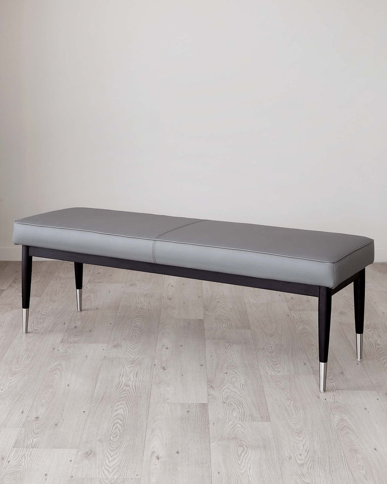 Modern grey upholstered bench with a sleek black wooden frame and metallic accents on the legs, set against a neutral backdrop.