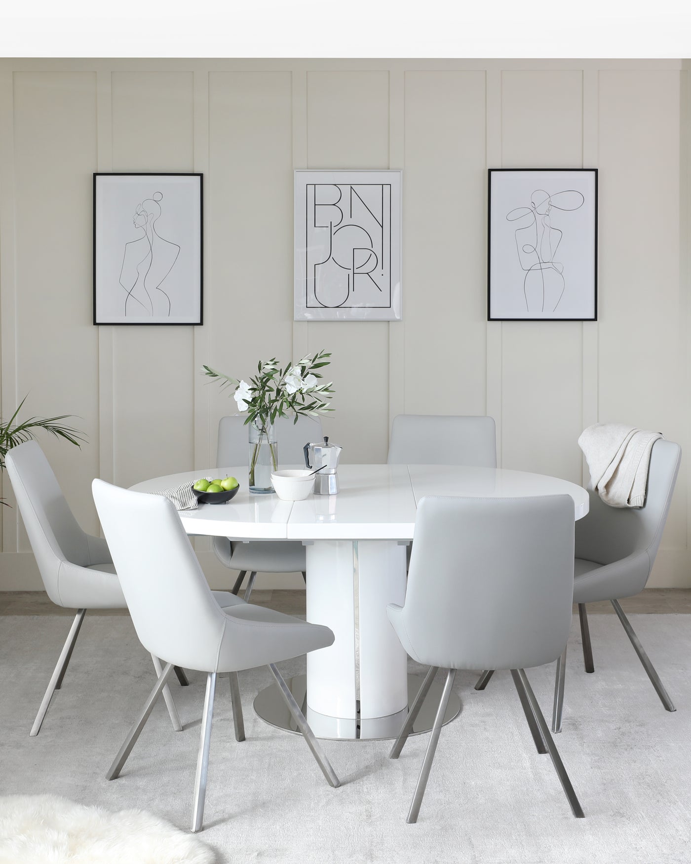 Modern dining room furniture set featuring a round, white table with a glossy finish and central pedestal base, paired with sleek grey upholstered chairs with metallic legs.