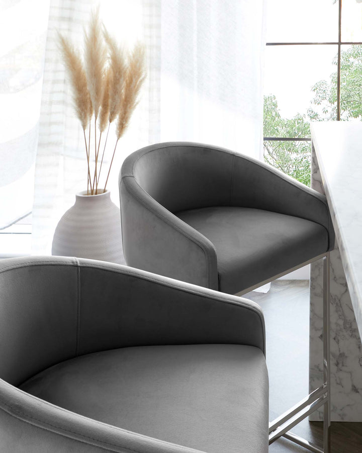 Two elegant grey upholstered armchairs with a smooth, curved design and a sleek, contemporary look.