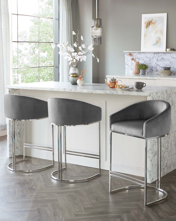 Two modern bar stools with grey velvet upholstery and chrome legs, situated at a white marble kitchen island.