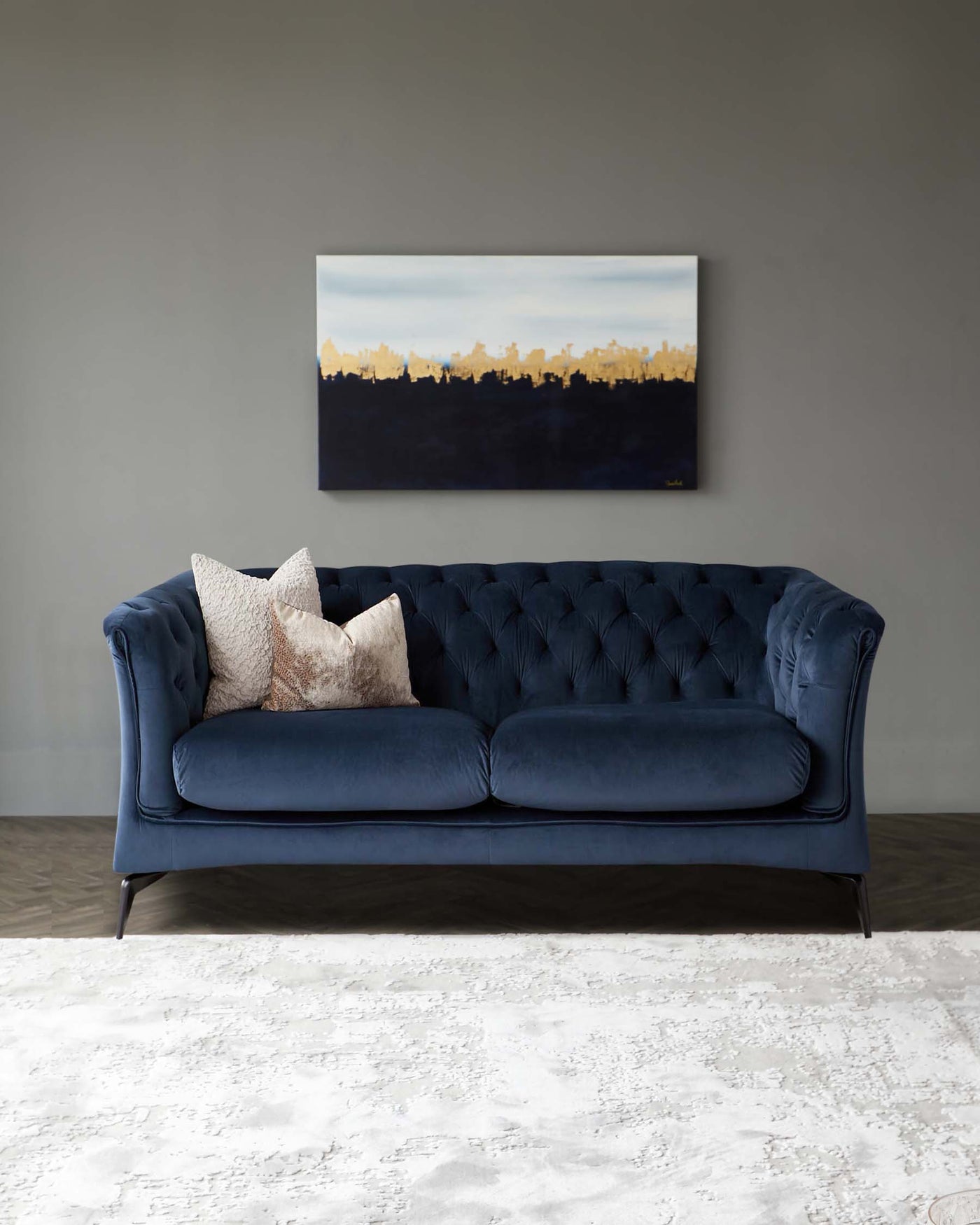 Elegant tufted navy blue velvet sofa with three plush cushions and scrolled arms, set atop tapered dark wooden legs on a textured off-white area rug.
