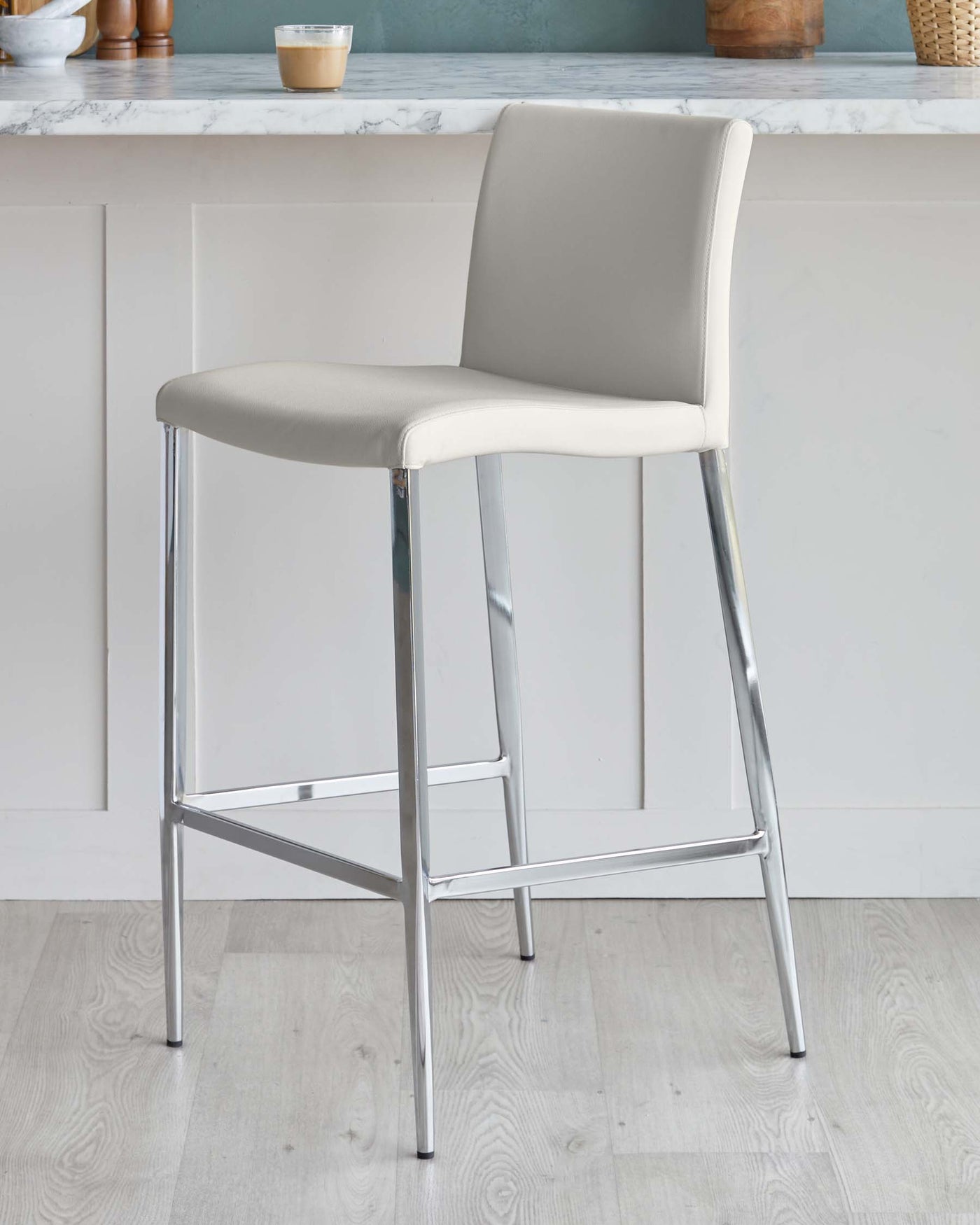 Modern bar stool with a sleek chrome frame and a taupe-coloured, upholstered seat and backrest.