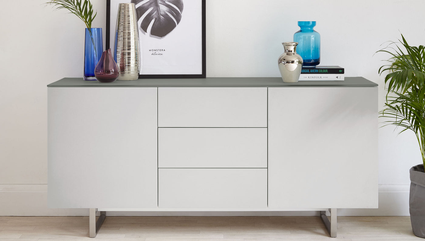 Modern minimalist sideboard in matte white with a sleek grey top, featuring a symmetric design with four doors and integrated handles, elevated on metal legs. Perfect for contemporary interiors.