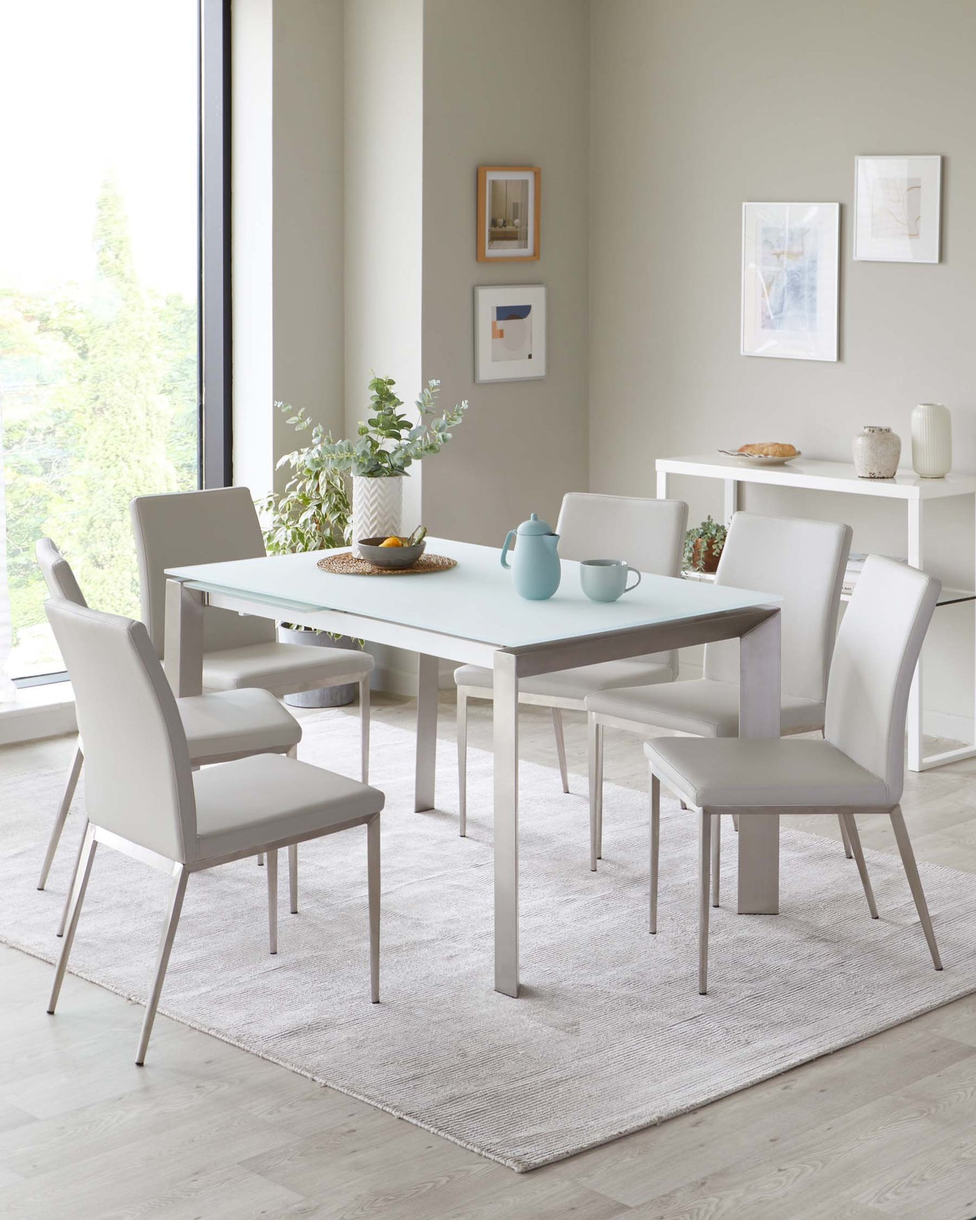 Modern minimalist dining furniture set featuring a clean-lined white rectangular table and six sleek white upholstered chairs on a light grey area rug. A small white console table is also present against the wall.