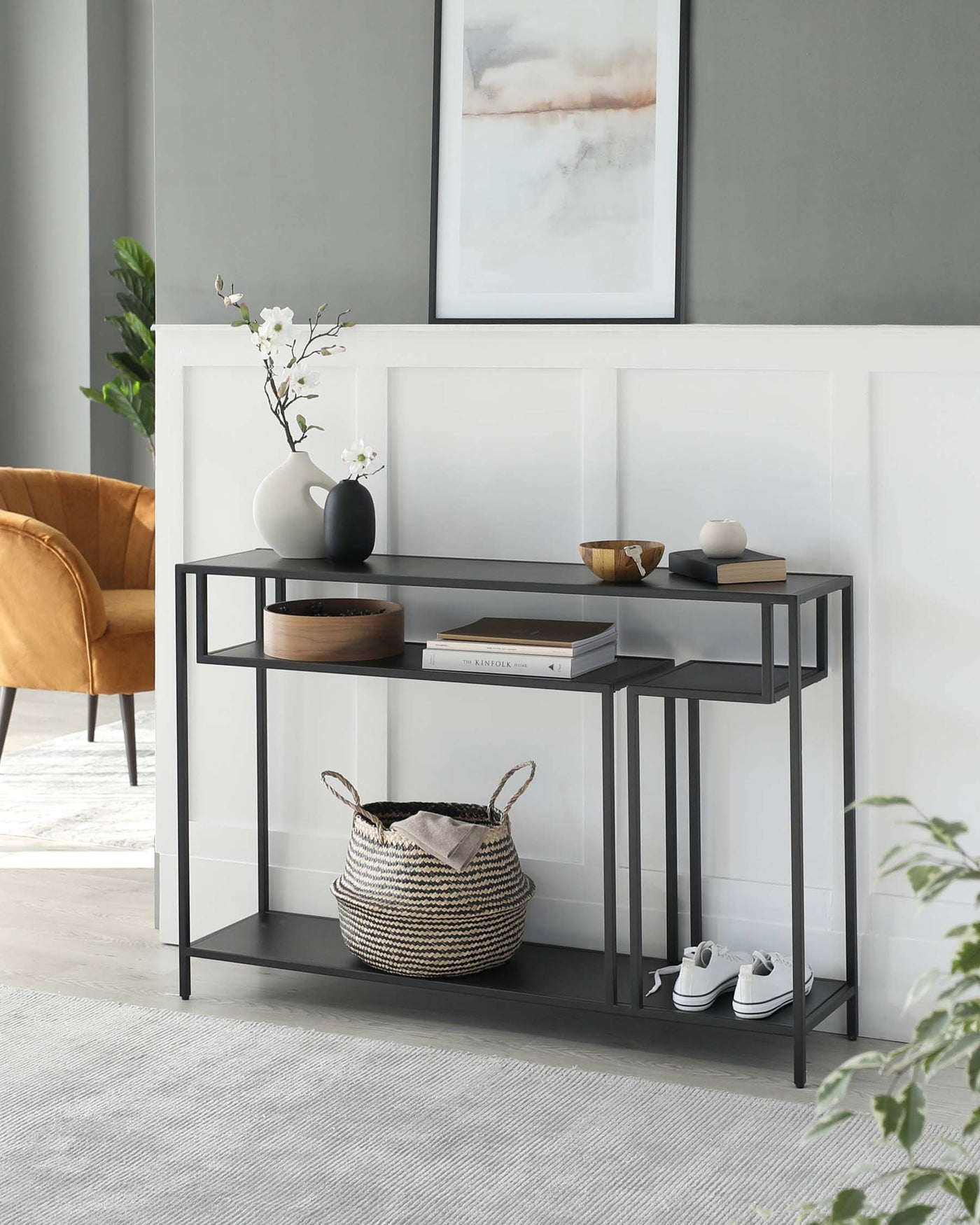 Modern console table with a sleek black metal frame and two-tiered tabletop in a contrasting light wood finish, ideal for hallway or living room decor.