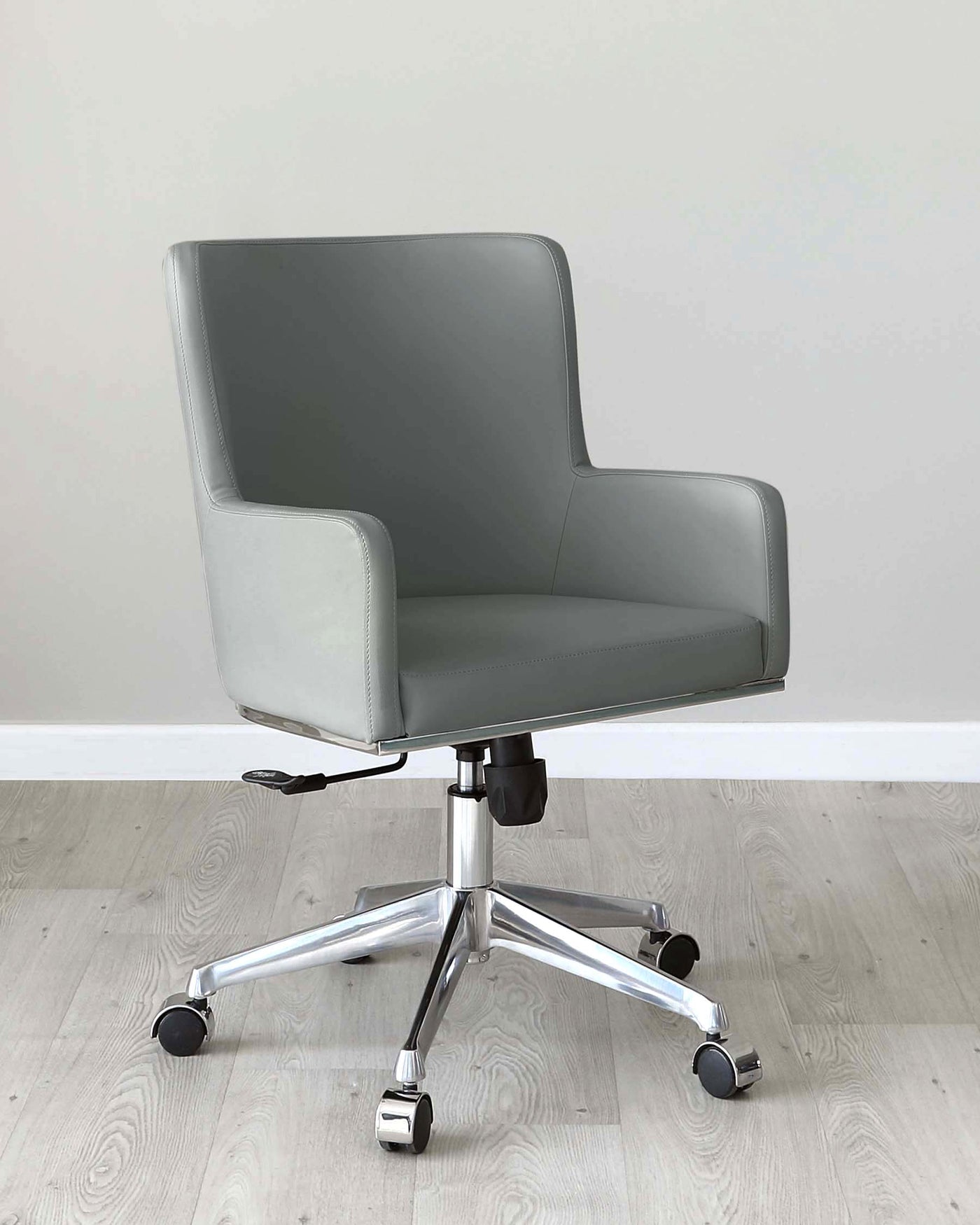 Modern office chair with a sleek grey upholstered seat and backrest, featuring a wide seat, gently curved armrests, and white stitching detail. Chair stands on a five-point chrome base equipped with caster wheels for ease of mobility, and includes a gas lift mechanism for height adjustment.