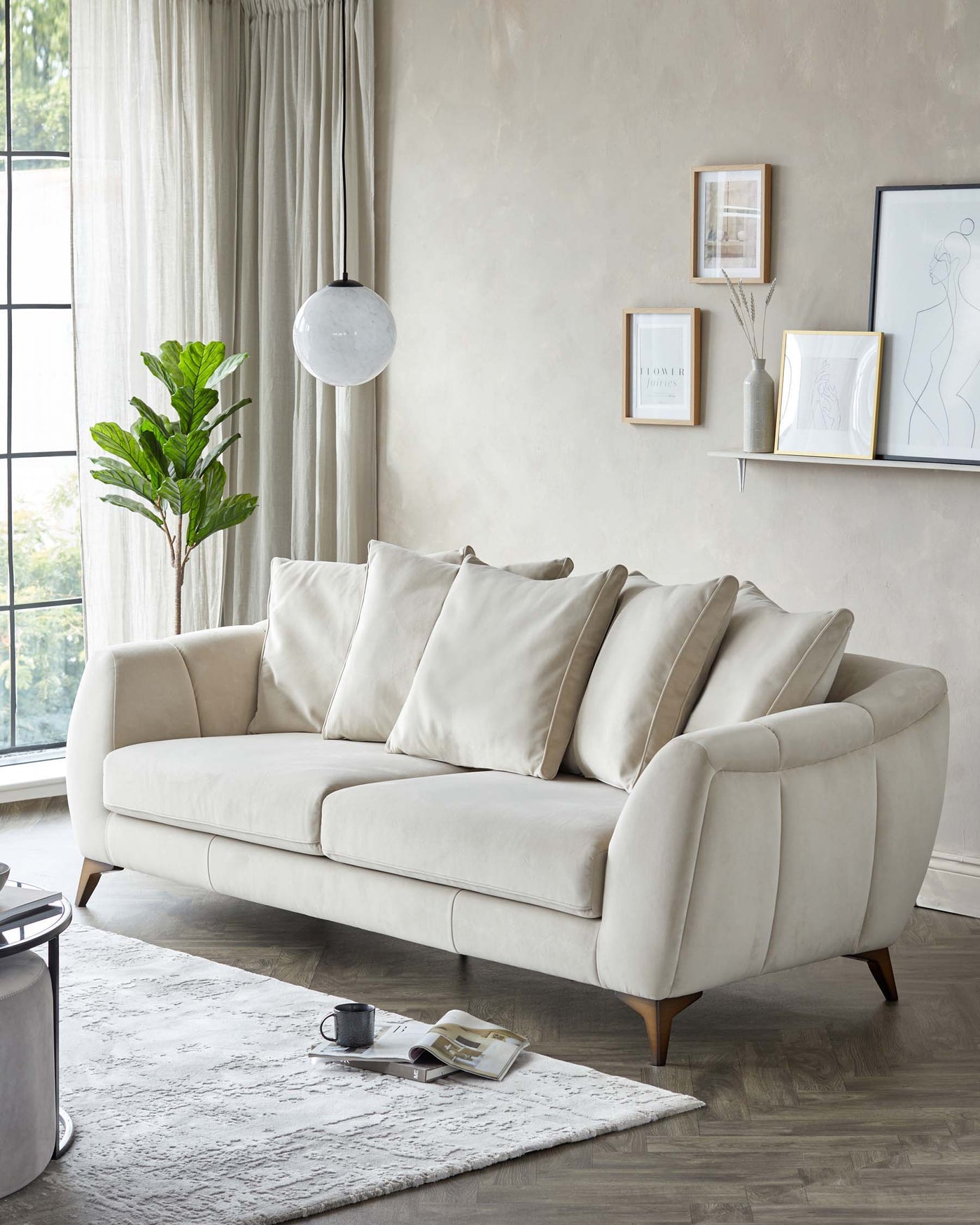 Elegant contemporary three-seater sofa with plush cream upholstery and angled wooden legs, accompanied by a small round black side table with a chrome base. A light grey textured area rug lies beneath the sofa, enhancing the modern aesthetic of the setting.