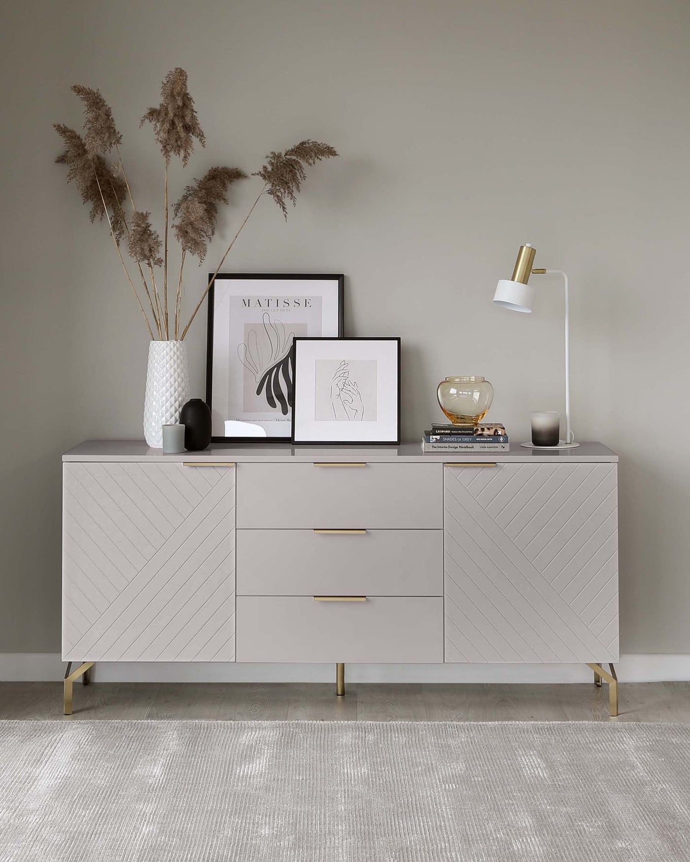 Modern light grey sideboard with chevron patterned front, brass handles, and legs.