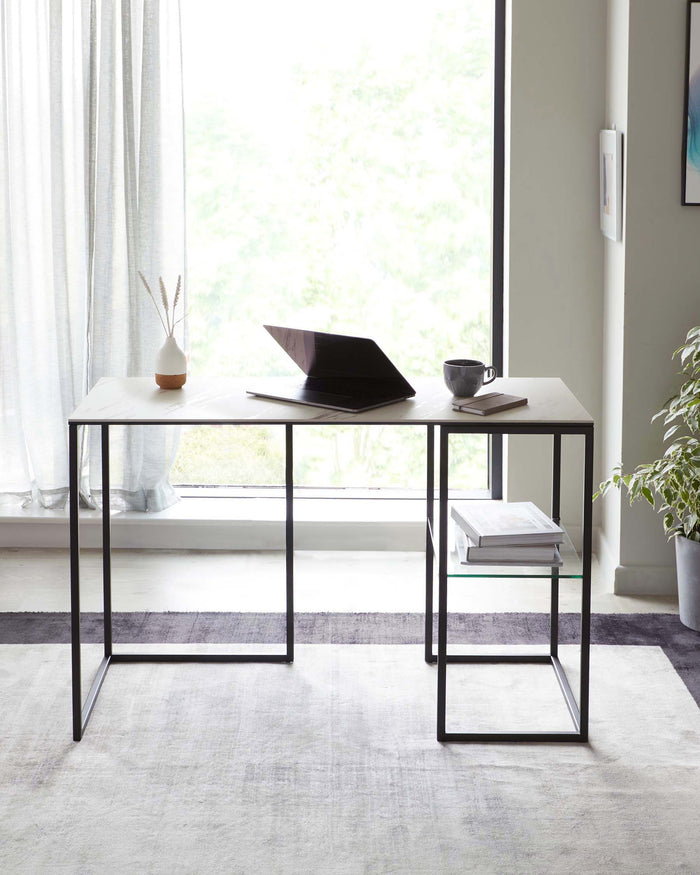 A minimalist white rectangular desk with slender black metal legs. The desk has a sleek, modern design with an additional glass shelf underneath for storage, situated in a bright room with a window, curtains, and a serene view.