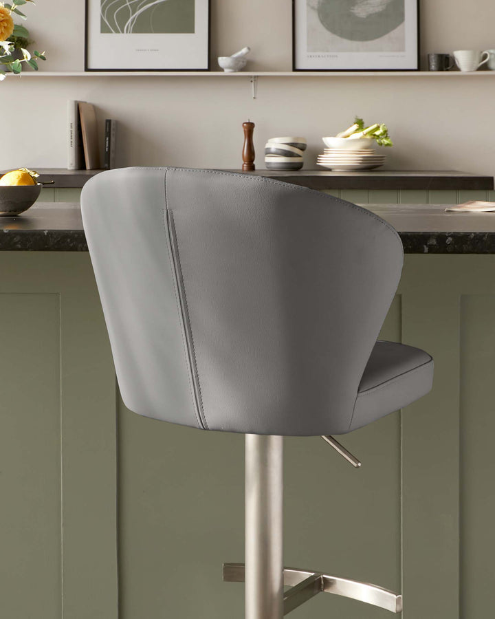 Contemporary grey upholstered bar stool with a curved backrest and a brushed stainless steel pedestal base, featuring a sleek footrest and visible stitching details.