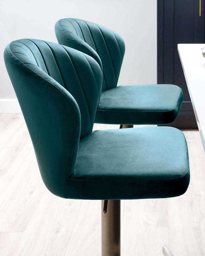 Elegant teal velvet dining chairs with vertically channelled backrests and smooth, padded seats, featuring sleek metal legs.