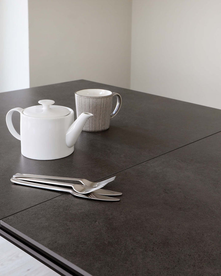 Modern dark grey dining table with a matte finish and sharp, clean lines.