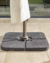 A sturdy, gray umbrella base securely holding an umbrella, designed for patio use, set on a tiled floor.