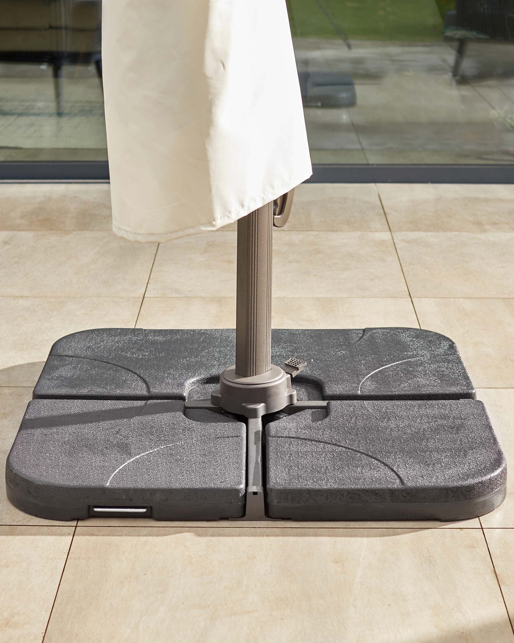 A sturdy, gray umbrella base securely holding an umbrella, designed for patio use, set on a tiled floor.